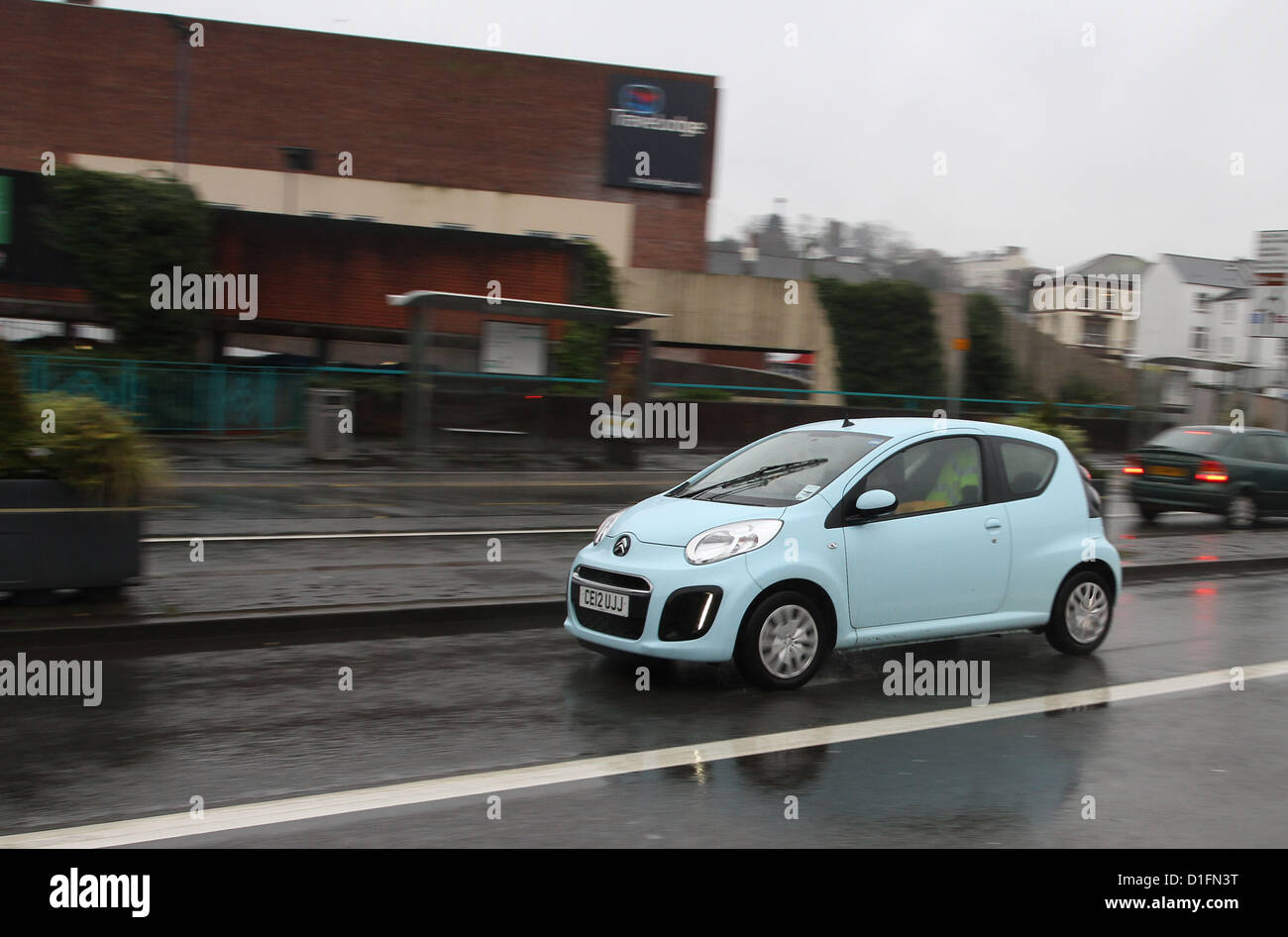 Pale blue Citroen C1 at speed in the Welsh city of Newport on a wet day with its reflection in the road, December 2012 Stock Photo