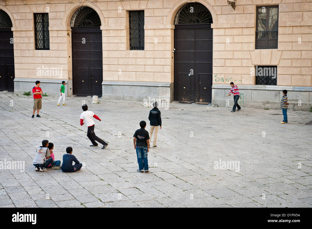 Bangladeshi migrant boys play cricket in a Square in old Palermo, Italy Stock Photo