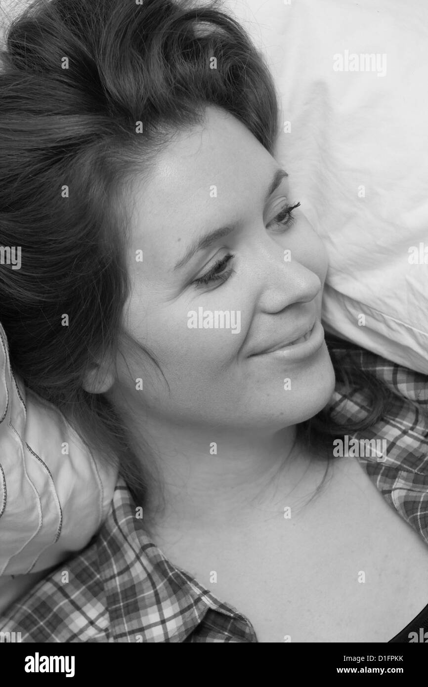 Girl smiling whilst lying on a bed Stock Photo - Alamy