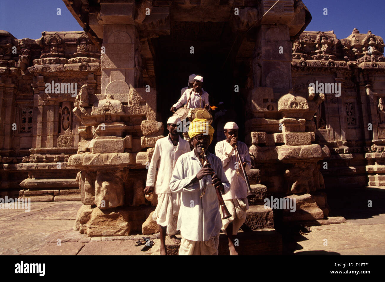 Men playing the Shehnai musical instrument during a religious procession amid the ruins of 8th century Chalukya monuments in Pattadakal, also spelled Paṭṭadakallu in Karnataka state India Stock Photo