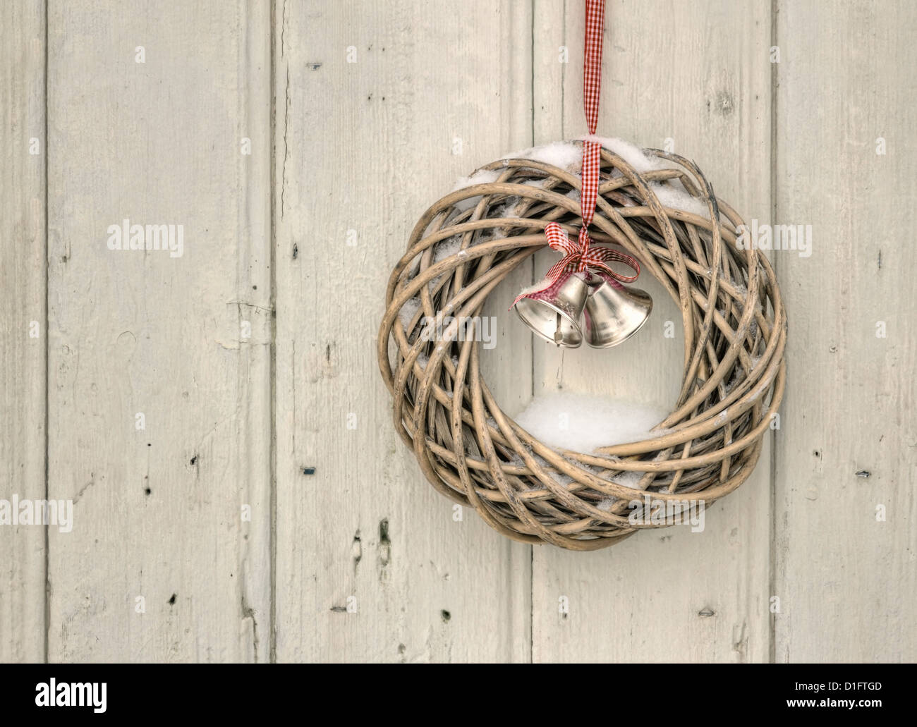 Christmas wreath with red ribbon and golden bells on a vintage wooden