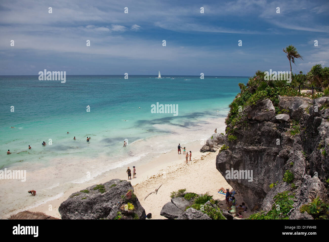People swimming on the beautiful beach below the spectacular Mayan ruins at Tulum. Stock Photo