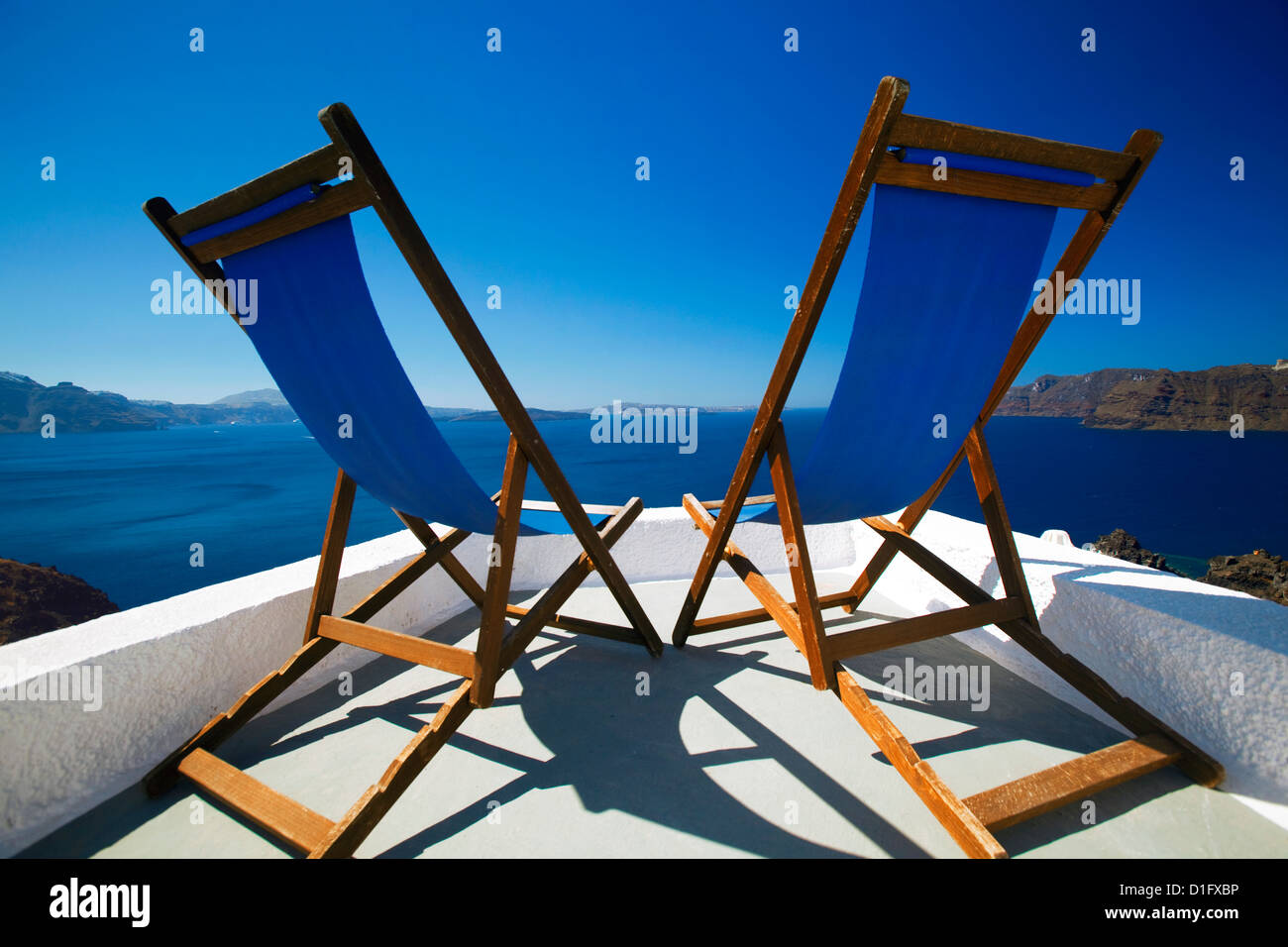 Deck chairs on terrace overlooking ocean, Santorini, Cyclades, Greek Islands, Greece, Europe Stock Photo