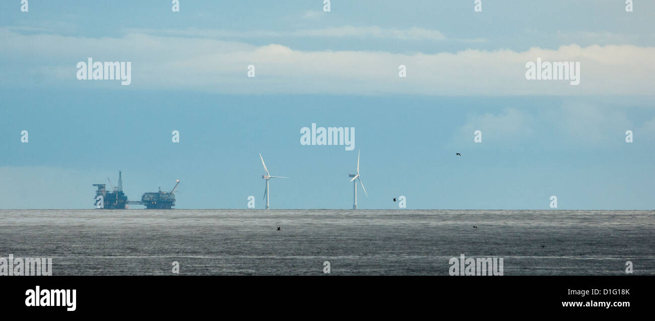 An oil / gas rig and off-shore windmills on the distant horizon. Stock Photo