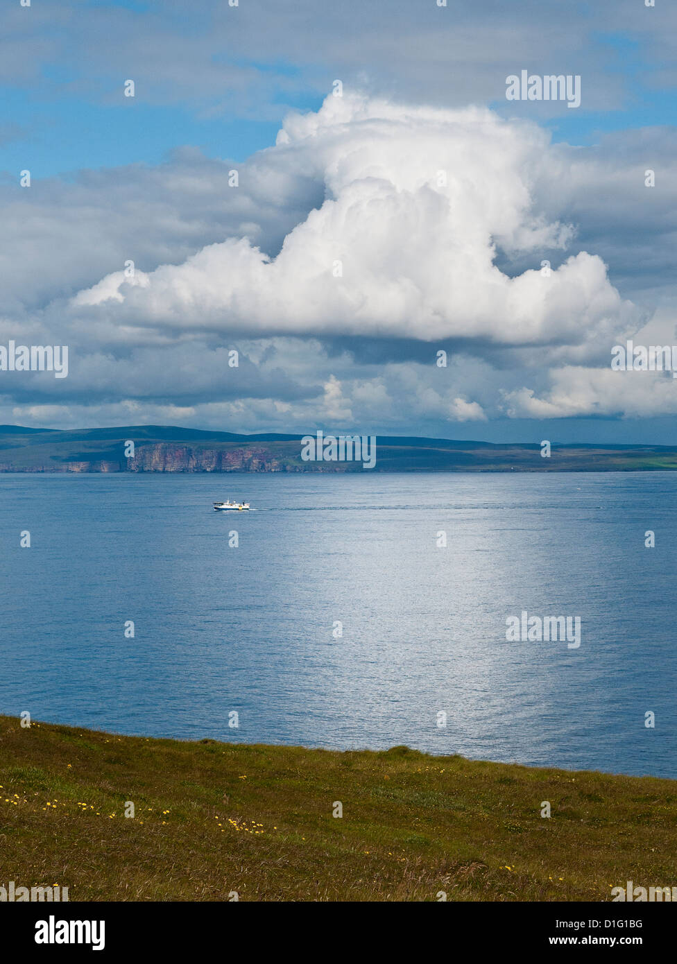 View from Dunnet Head towards Orkneys on a sunny day, with ferry crossing a calm sea, and distinct white cumulus clouds. Stock Photo