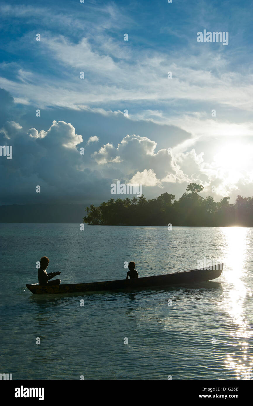 Boys in a canoe in backlit in the Marovo Lagoon, Solomon Islands, Pacific Stock Photo