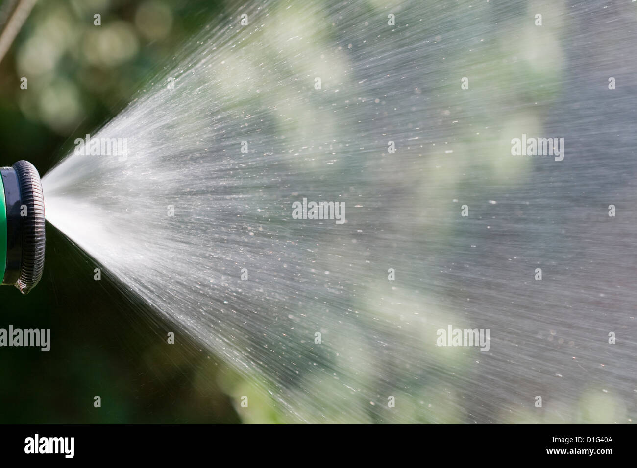 Lawn water sprinkler spraying water over grass in garden on a hot