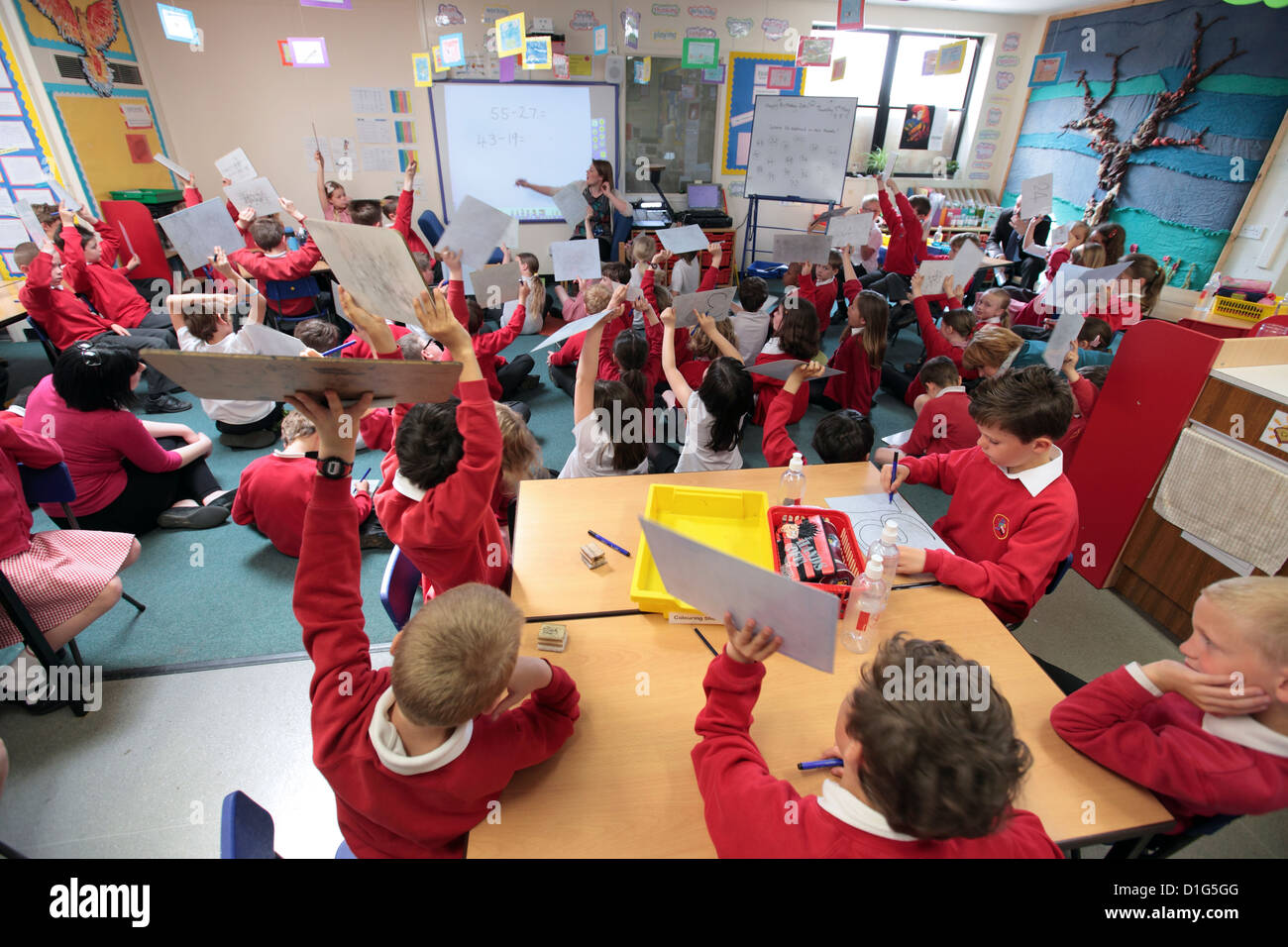 Primary junior school Mathematics Maths class, hands up with the answers, UK. Stock Photo