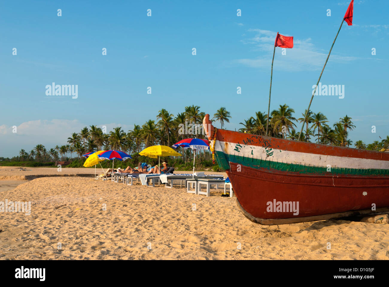 Traditional fishing boat and sunbathers on beach, Benaulim, Goa, India, Asia Stock Photo