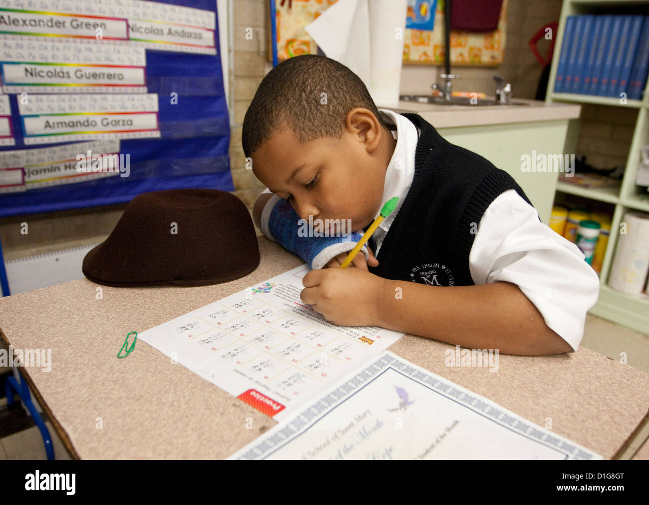 African-American boy in second grade elementary private Catholic school in Texas does school work at desk in classroom Stock Photo