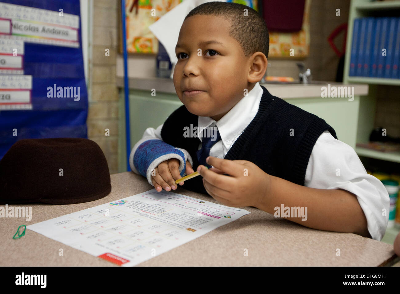 African-American boy in second grade elementary private Catholic school in Texas does school work at desk in classroom Stock Photo