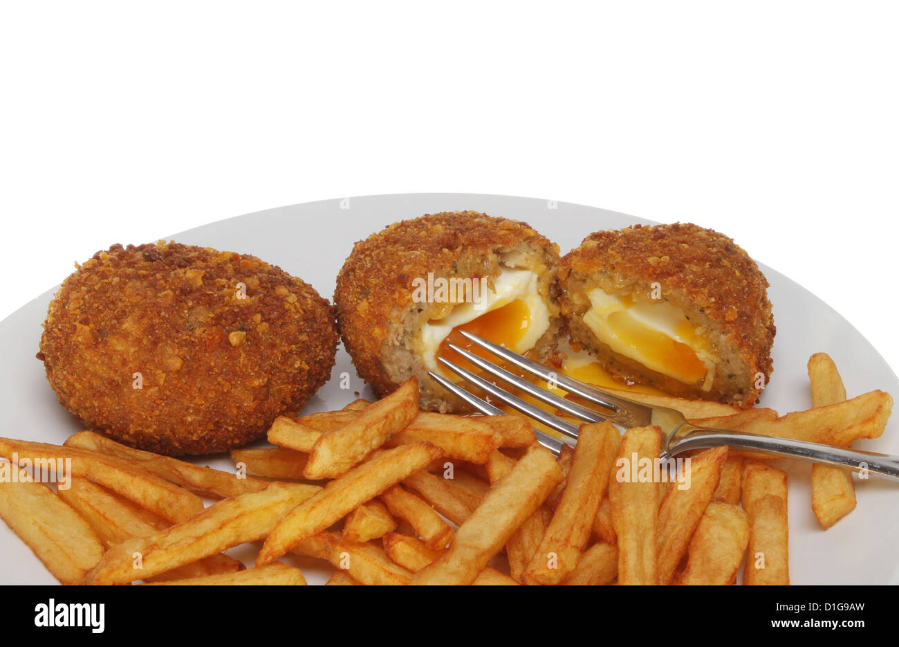 Runny yolk Scotch eggs and chips with a fork on a plate Stock Photo
