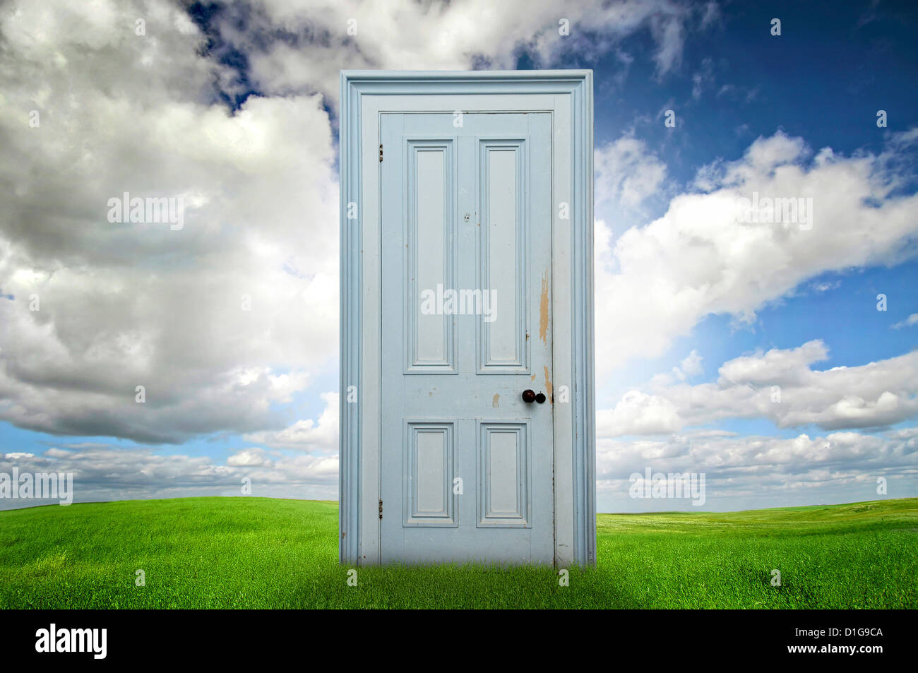 Isolated door in a grass field with blue cloudy sky Stock Photo