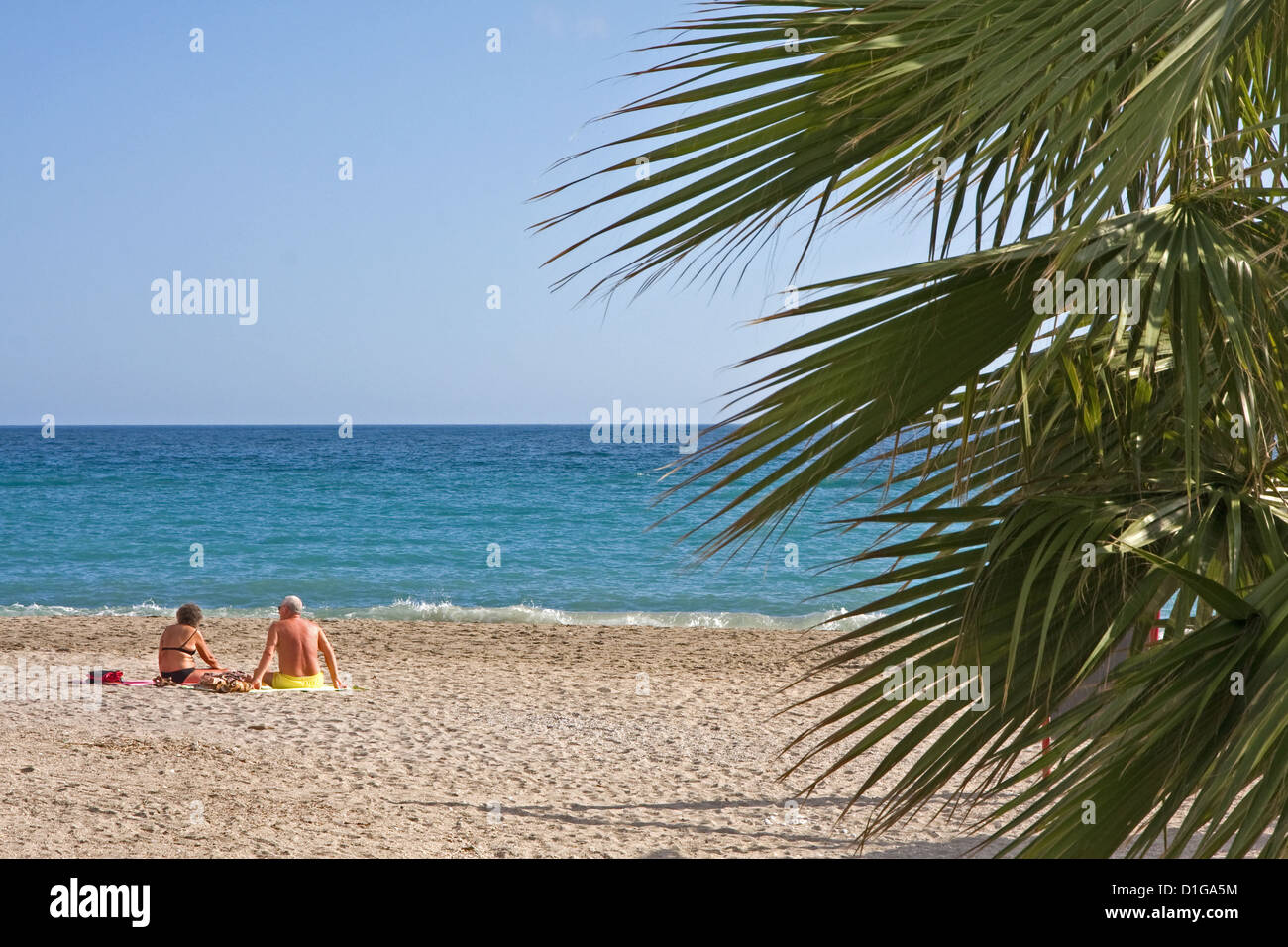 Middle aged couple enjoying sun on Playa de Burriana, Nerja, Spain Stock Photo