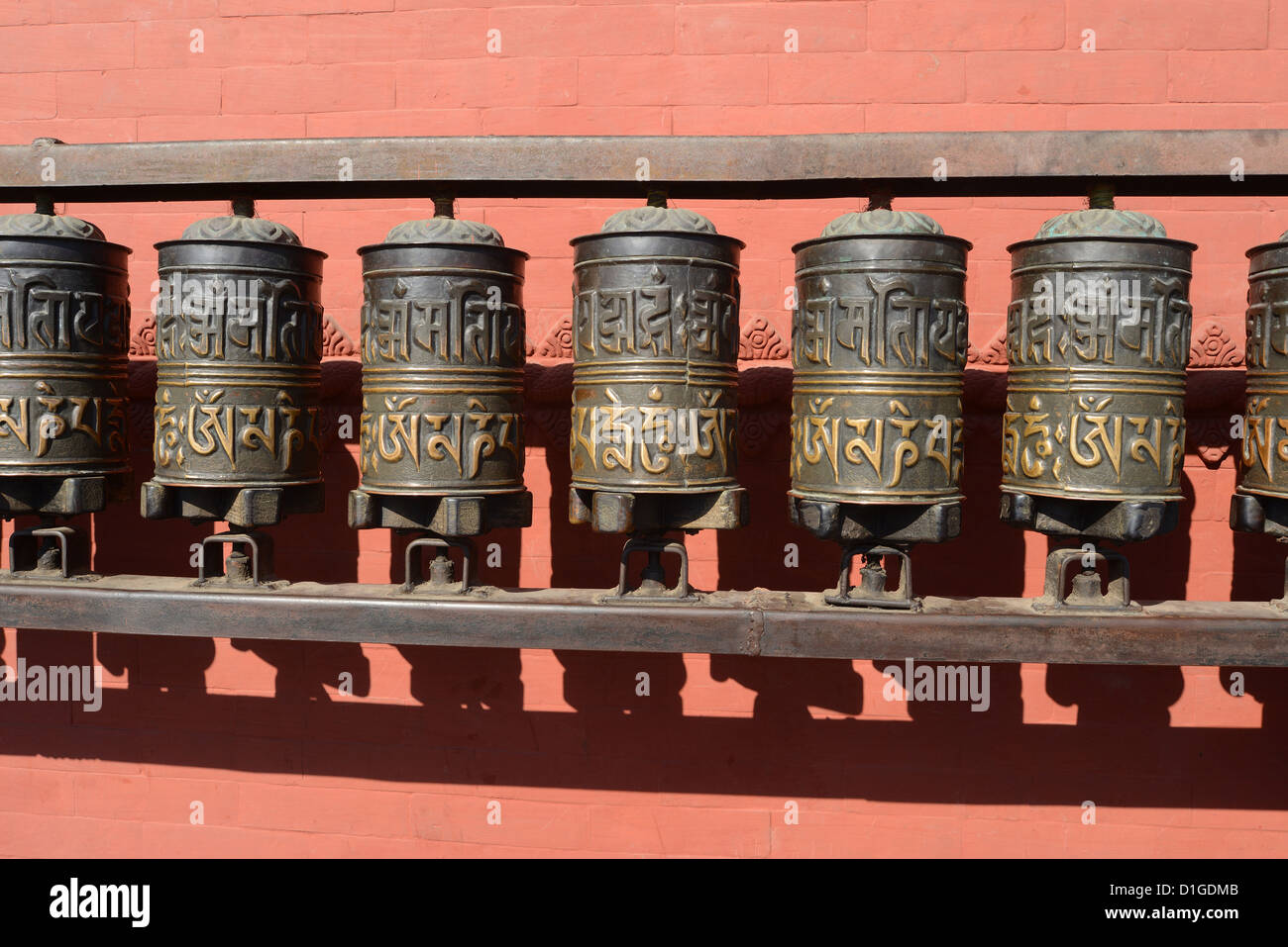 Buddhist prayer wheels in front of a red wall at Swayambhunath Stupa ...
