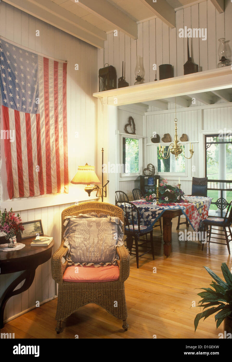 EATING AREAS Summer country home dining area flag hung on wall wicker chair wood walls quilt tablecloth country style charming Stock Photo