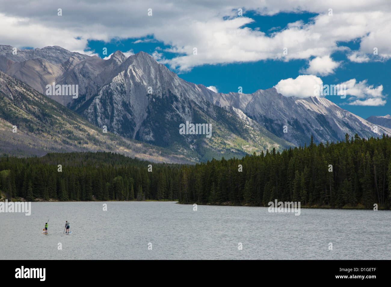 Two people on paddle boards on Johnson Lake near town of Banff in Banff National Park in the Canadian Rockies in Alberta Canada Stock Photo