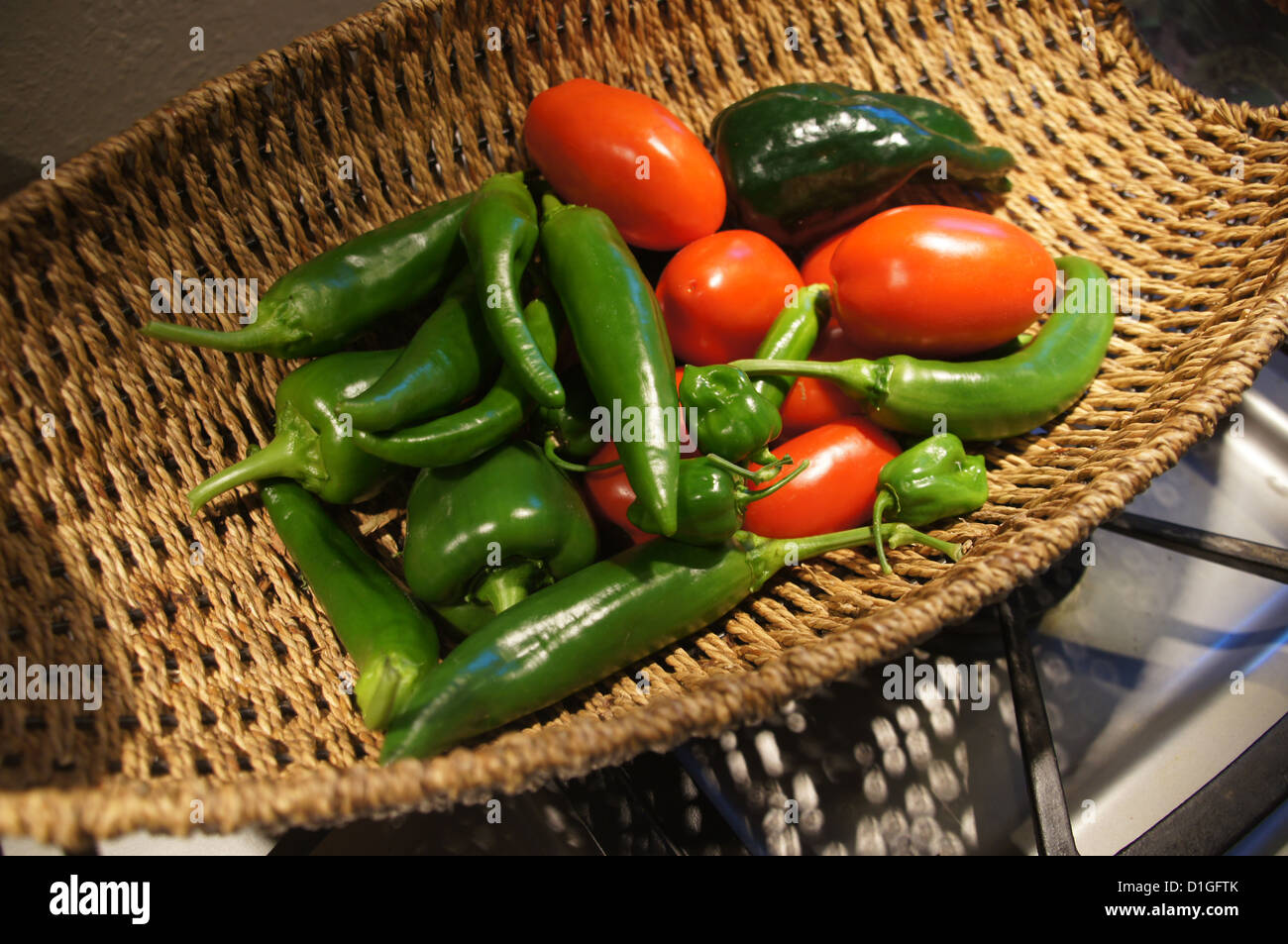 Fresh green peppers and red tomatoes in a wicker basket from a Seattle garden Stock Photo