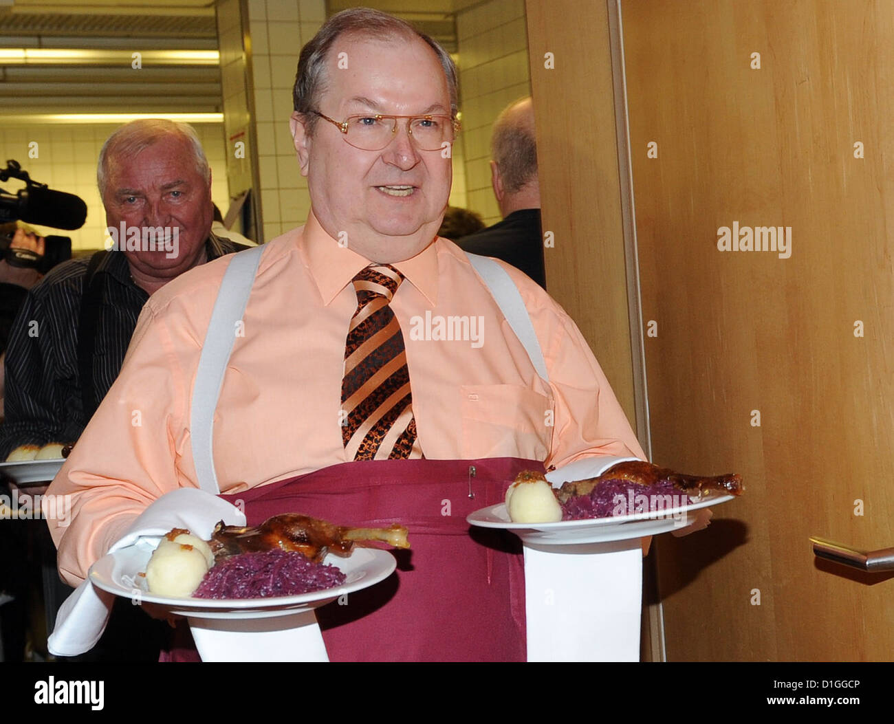 Burough mayor of Berlin-Neukoelln, Heinz Buschkowsky (SPD), serves roast goose at the traditional Christmas dinner for the homeless at Hotel Estrel in Berlin-Neukoelln, Germany, 19 December 2012. This Christmas dinner has been organized for 18 years by Frank Zander, charitable organization Diakonisches Werk and Hotel Estrel. Photo: BRITTA PEDERSEN Stock Photo