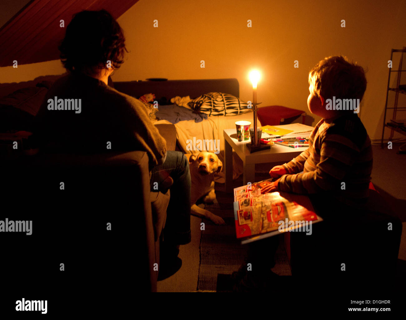 (ILLUSTRATION) An illustration dated 13 December 2012 shows a mother sits with her son in their dark home in Hanover, Germany. The room is lit by a candle. In November, the family went two and a half weeks without electricity after the municipal works turned off their power because of unpaid bills. Photo: JULIAN STRATENSCHULTE Stock Photo