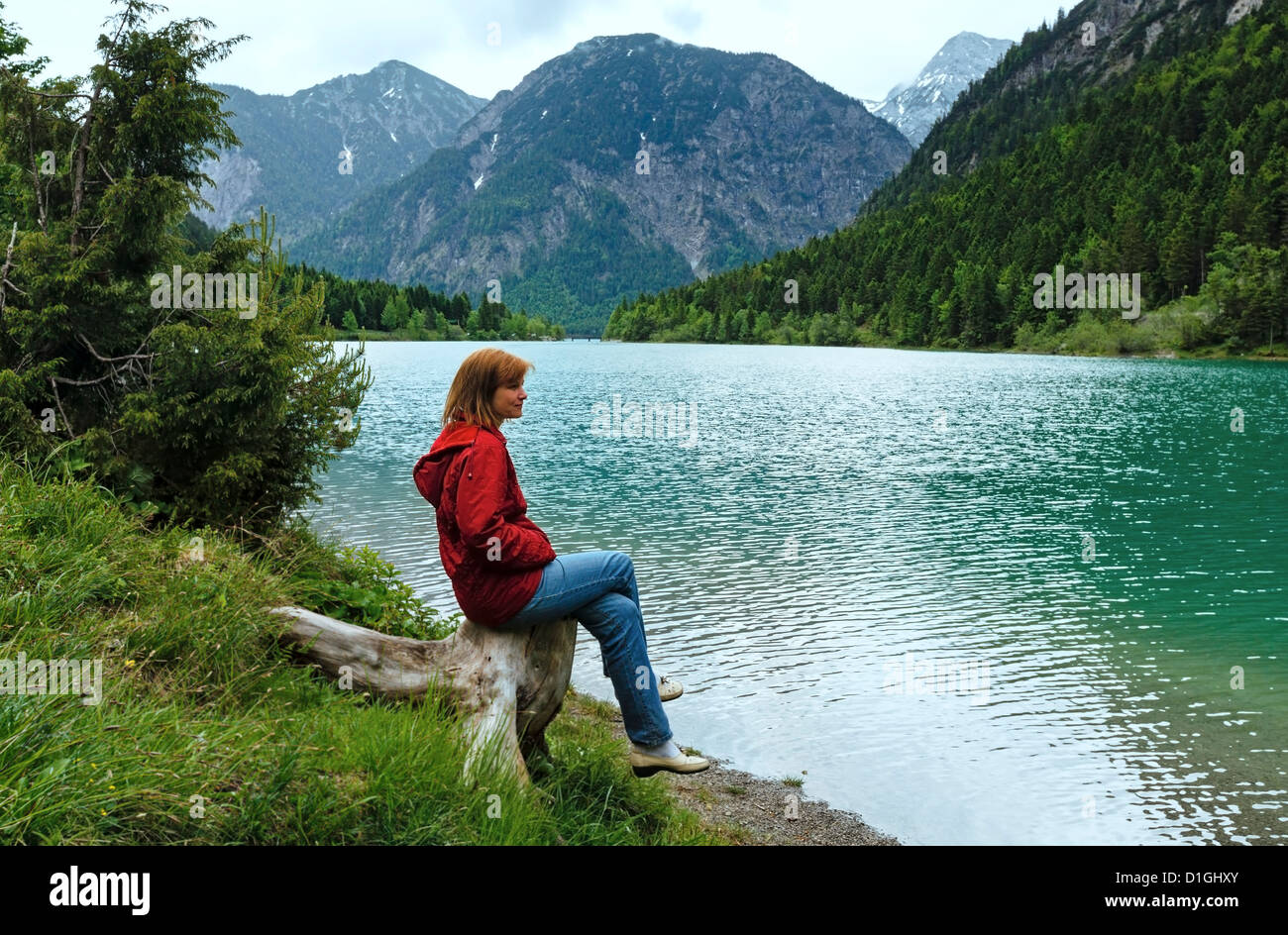Plansee summer landscape and woman on stump in front. Overcast day. (Austria). Stock Photo