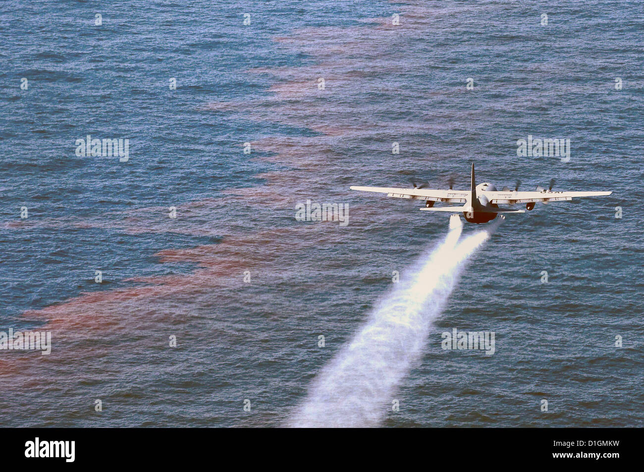A US Air Force C-130 Hercules drops oil-dispersing chemicals over an oil slick as part of the Deepwater Horizon Response effort May 5, 2010 in the Gulf of Mexico. Stock Photo