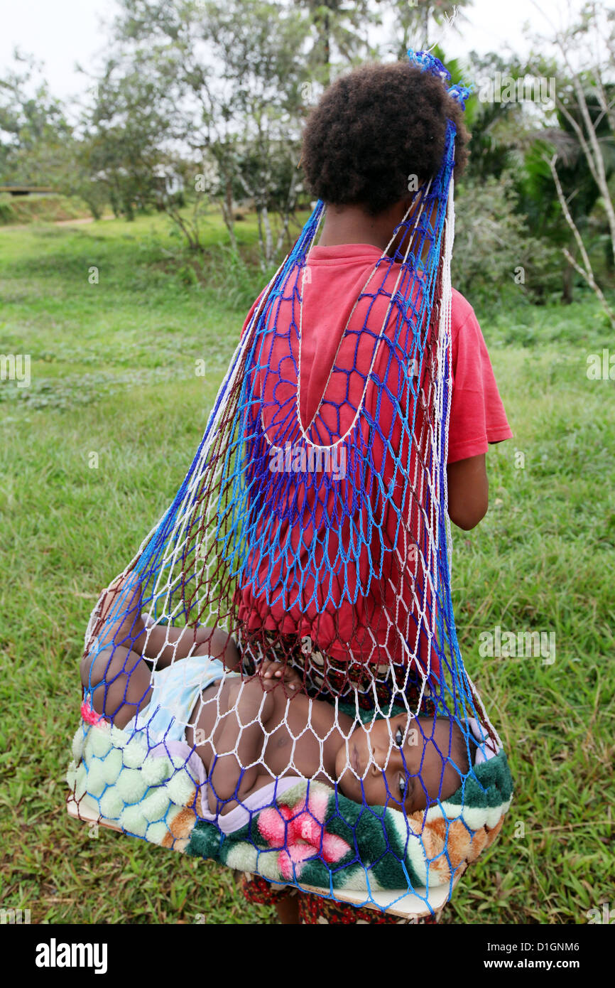 Girl carries her baby sister in a traditional woven bilum hanging from her  head, Papua New Guinea Stock Photo - Alamy