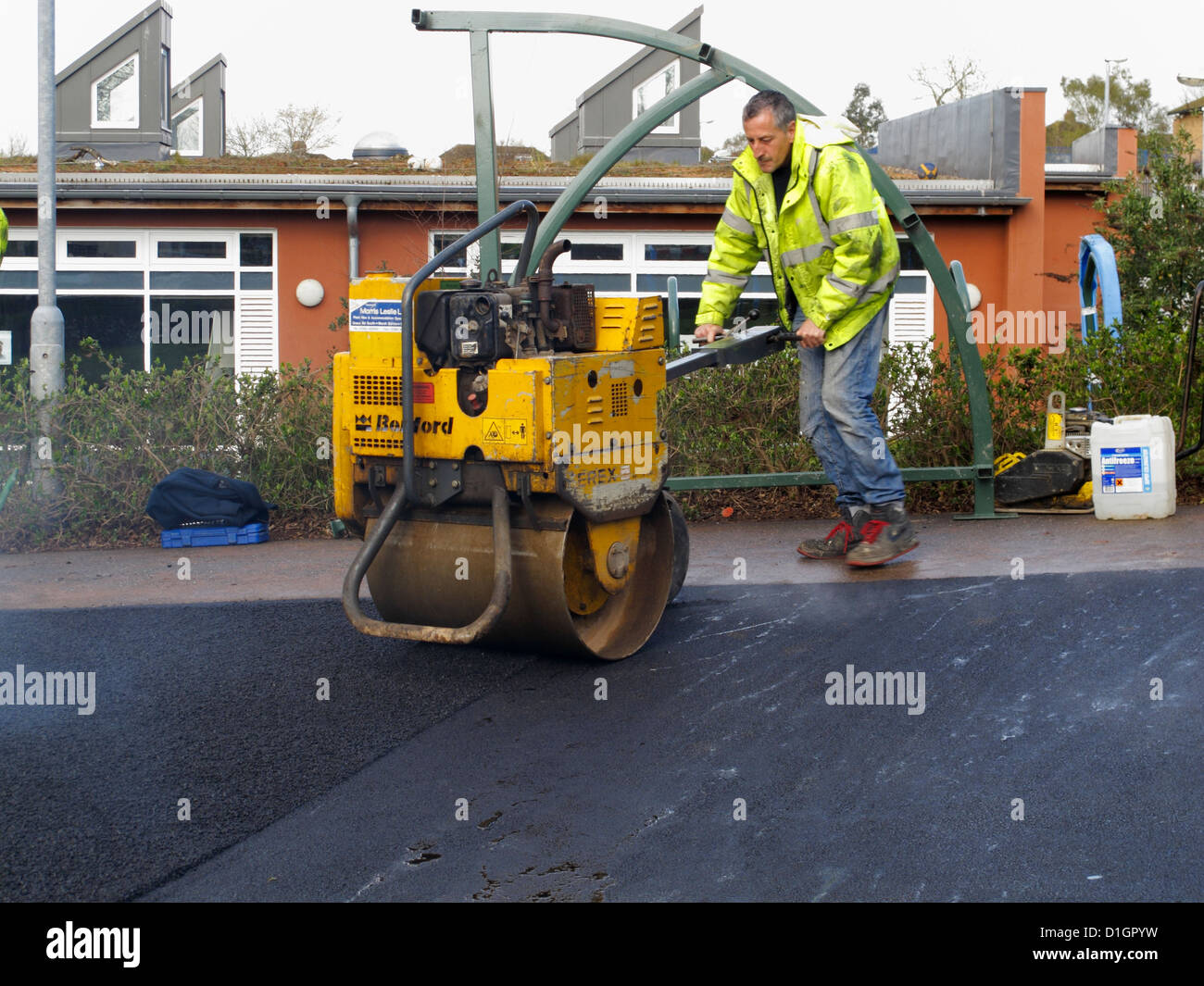 Roadworker operation a self propelled roller on binder course asphalt