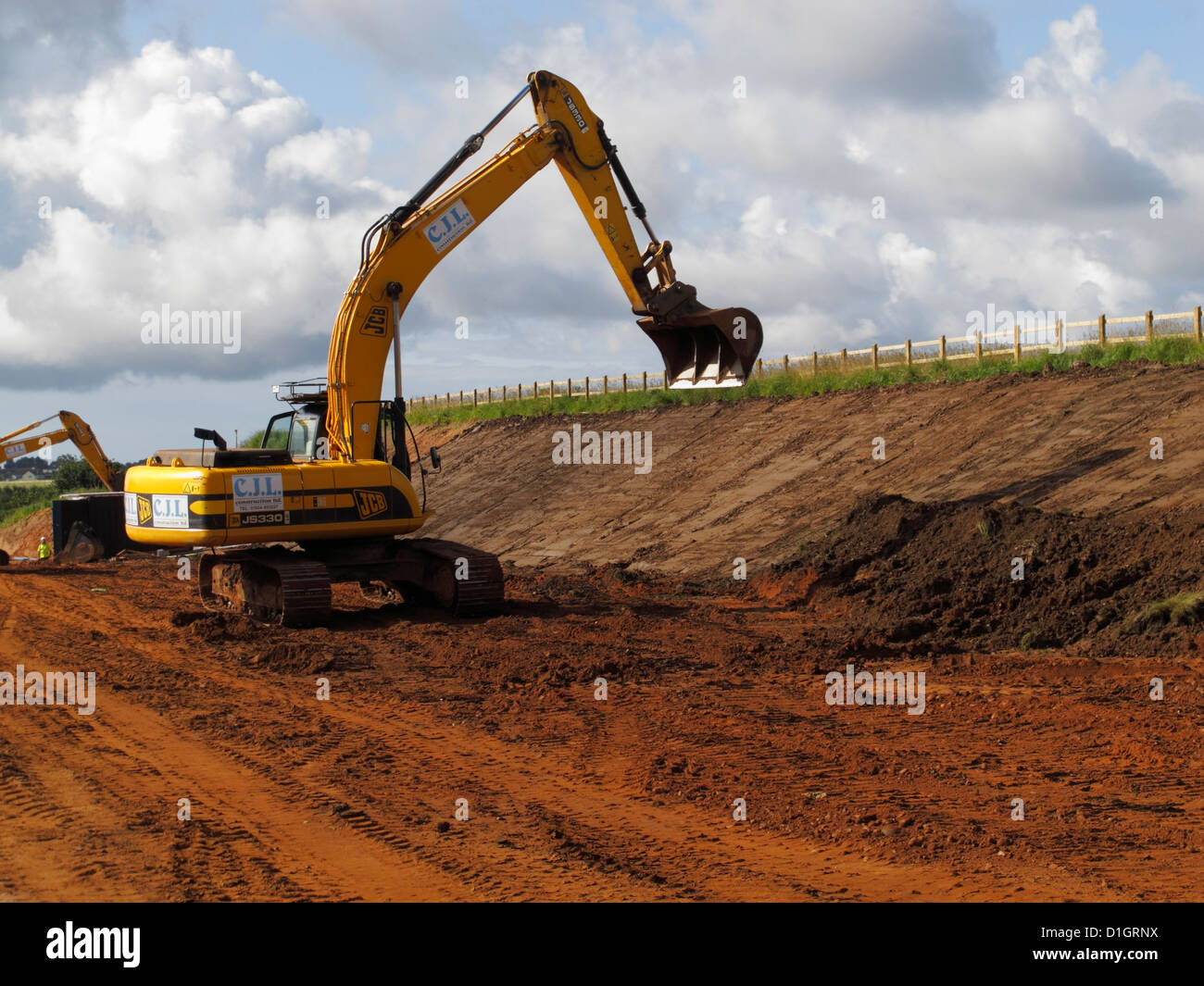 Bucket of large tracked JCB digger trimming cutting slope on new road