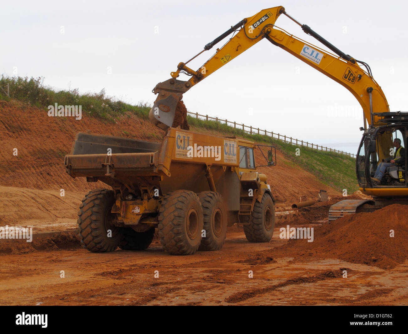 tracked backhoe digger loading large Volvo Dump truck site tipper  lorry road building site uk Stock Photo