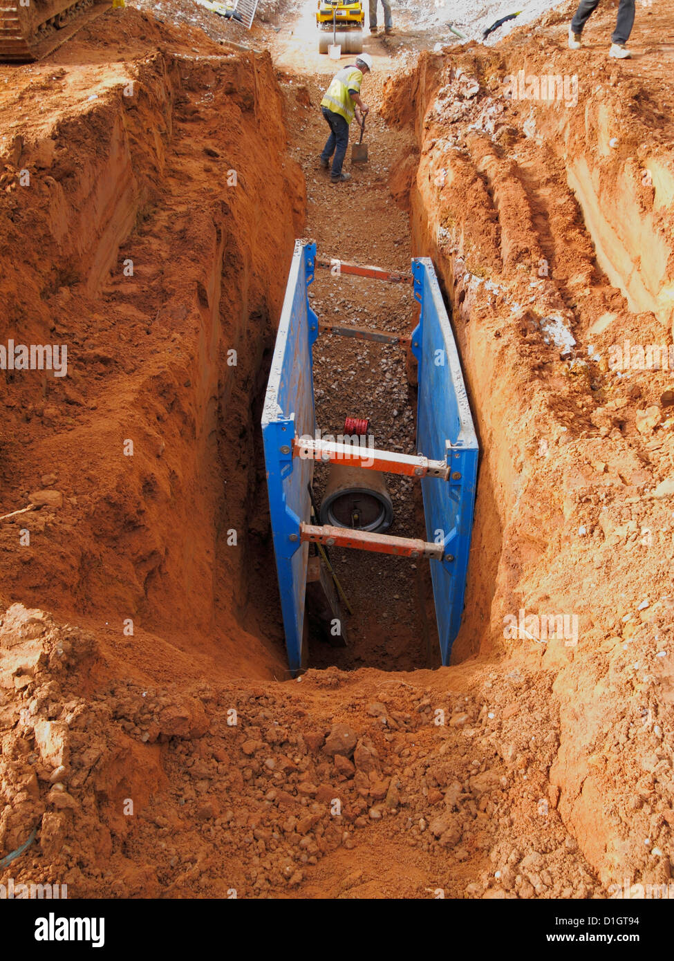 Men working in deep trench excavation under protection of  hydraulic shoring support system uk Stock Photo