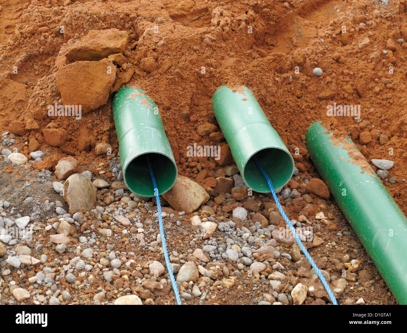 Road construction site UK trench with green ducts for cable TV and internet fibre-optic fiber optic communication cables Stock Photo