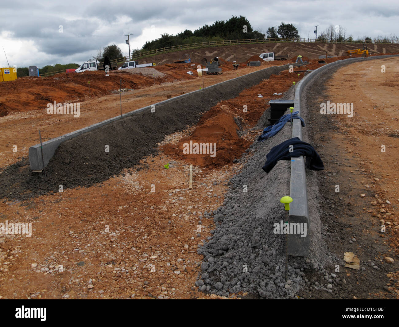 Lines of newly laid kerbs kerbing curbs concrete bedding and backing on road construction site UK Stock Photo