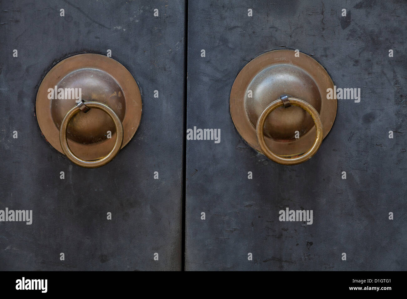 two brass door openers on a steel blue door Stock Photo