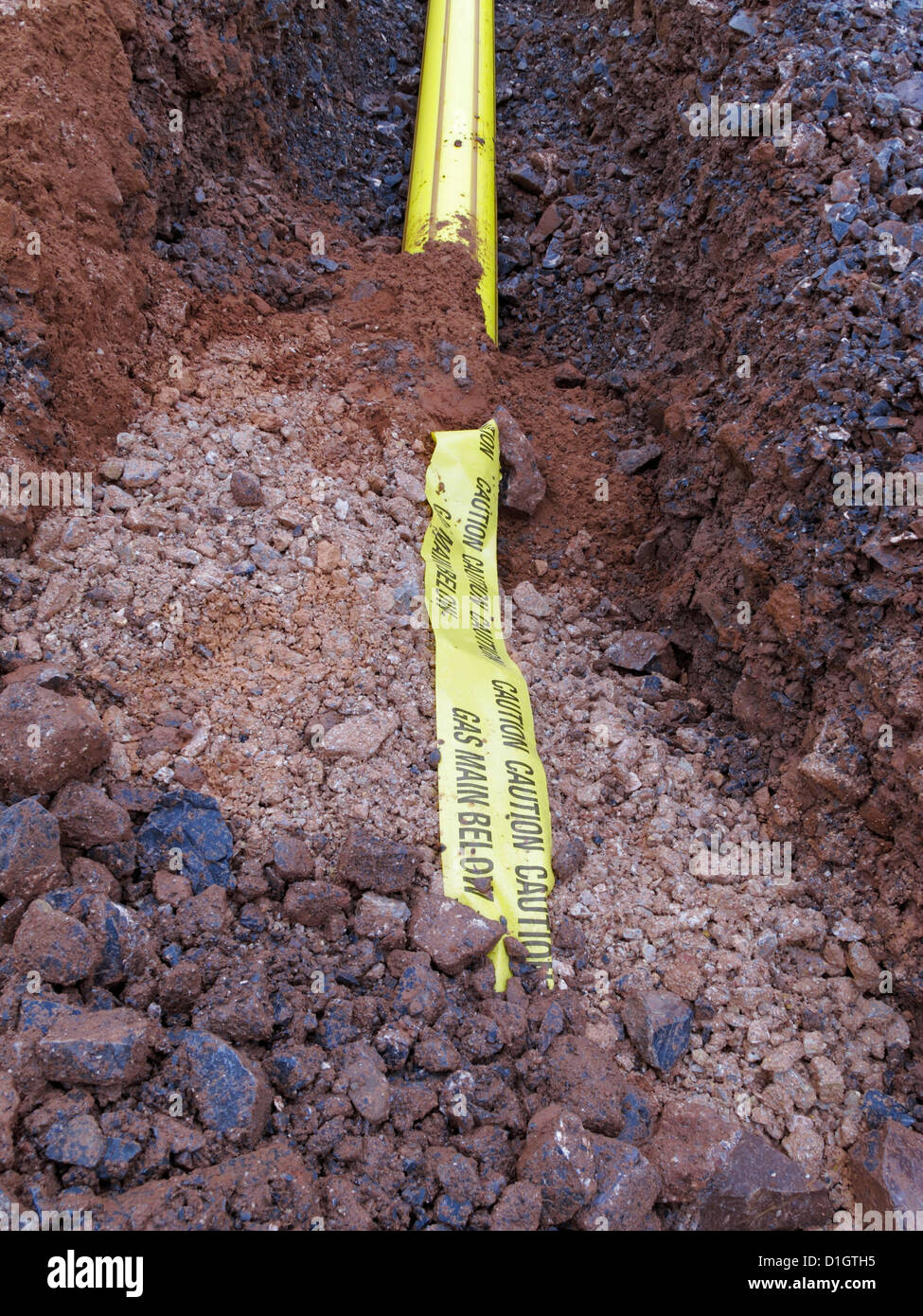 Road construction site UK trench with yellow tape warning of