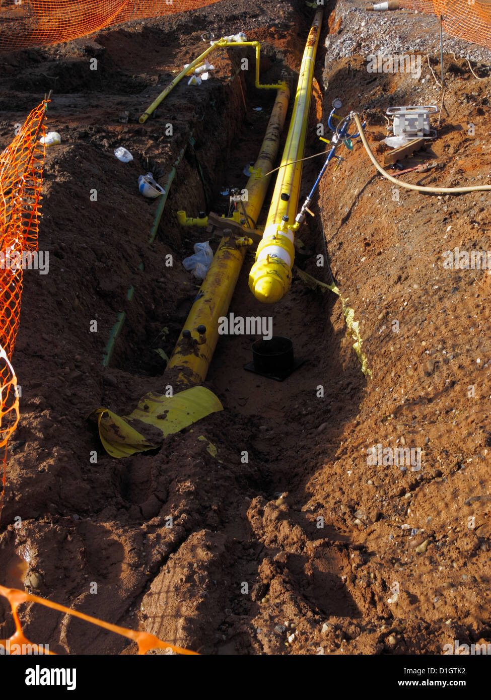 Newly laid High pressure yellow polythene gas main pipe in trench undergoing testing with pressure gauge in UK Stock Photo