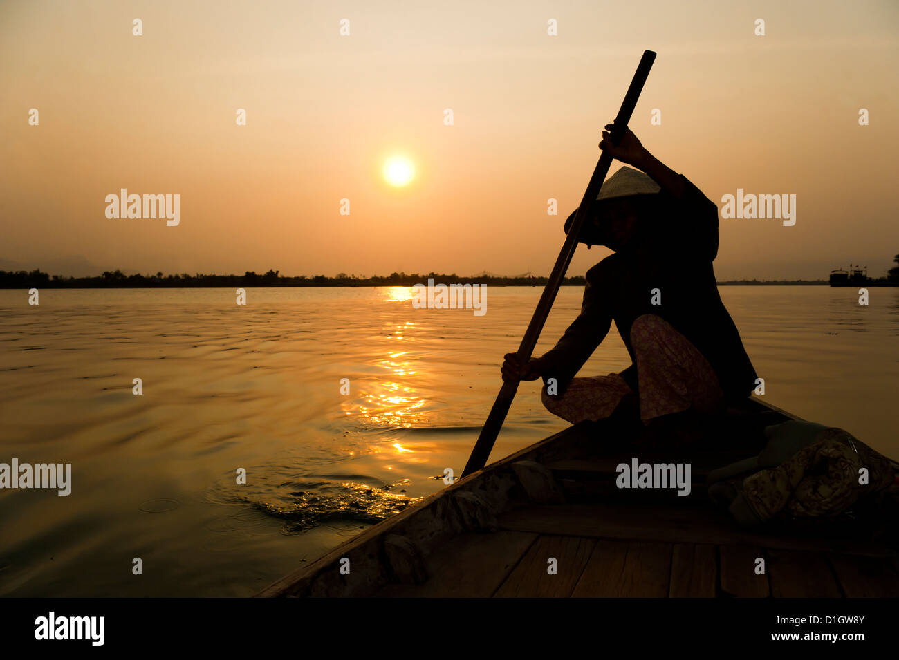 Old lady rowing in Hoi An harbour silhouetted at sunset, Vietnam ...