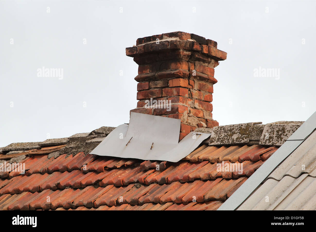 Old pipe from the furnace on the roof out shingles, on grey sky background Stock Photo
