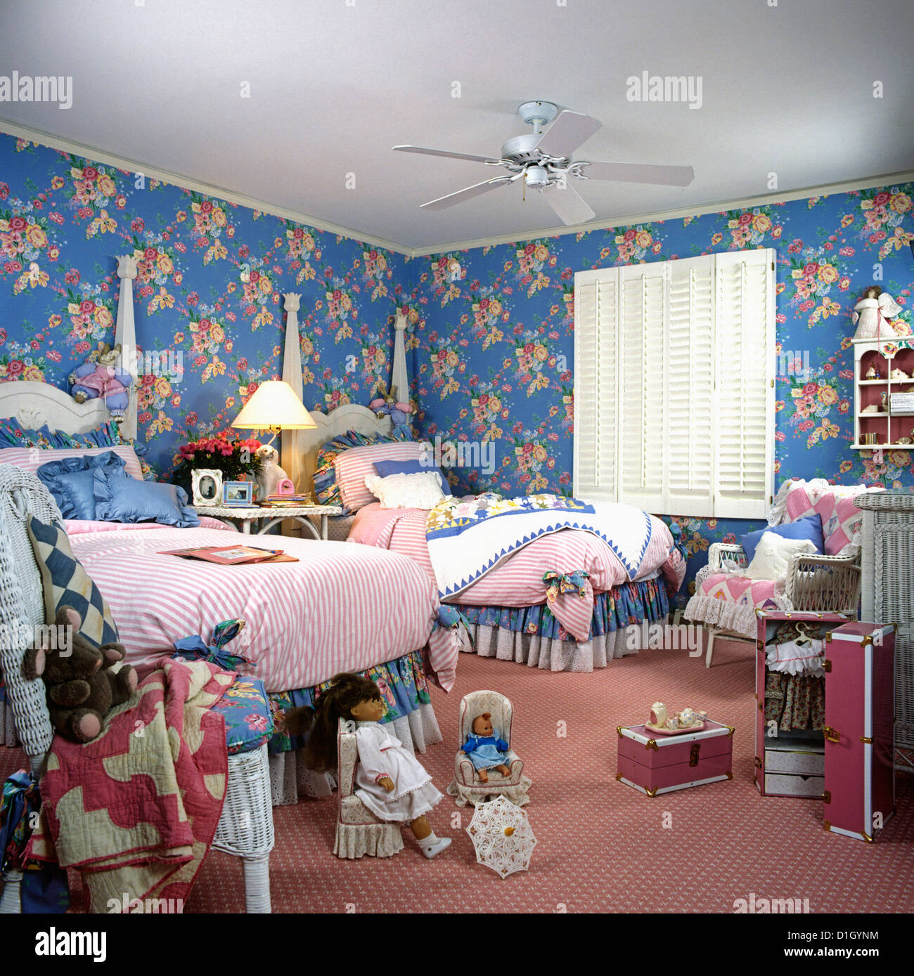 CHILDREN'S BEDROOM: Girl's twin two poster beds, blue and pink floral  walls. Pink rug. White wood shutters at window. Dolls Stock Photo - Alamy, image size:1300x1389