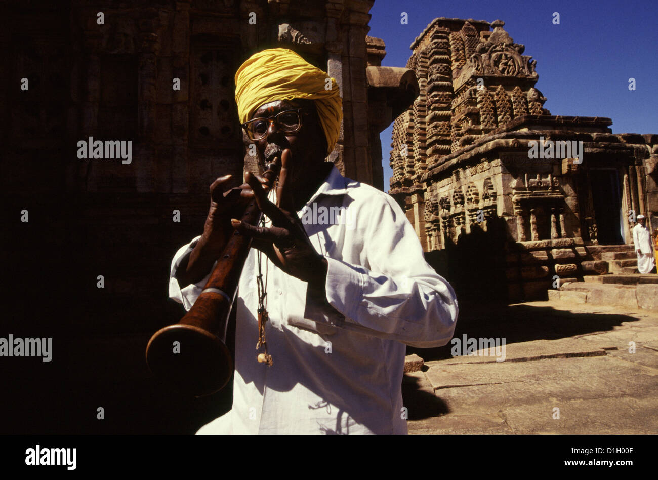 Man playing the Shehnai musical instrument during a religious procession amid the ruins of 8th century Chalukya monuments in Pattadakal, also spelled Paṭṭadakallu in Karnataka state India Stock Photo
