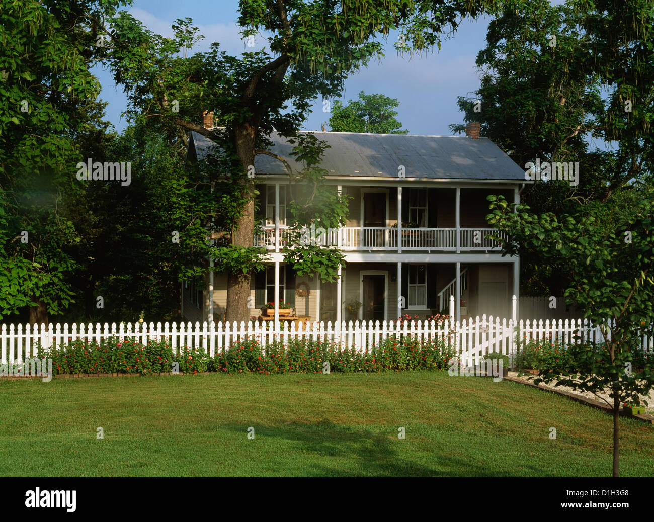 EXTERIORS: Two story home, white picket fence, porches on both levels run the length of the house Stock Photo