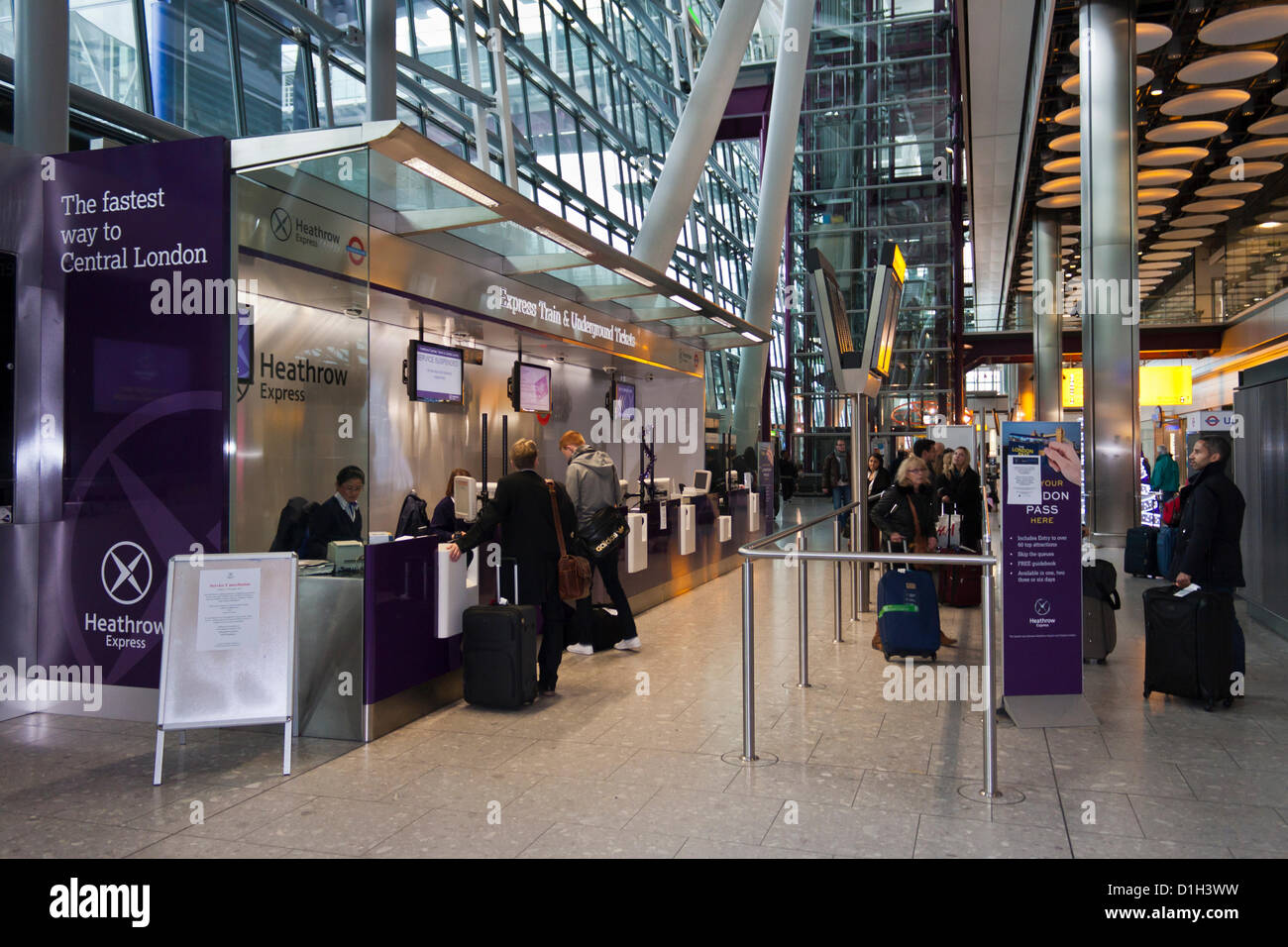 Arriving passengers at Heathrow wait in line for tickets on the Heathrow Express train into London. Stock Photo