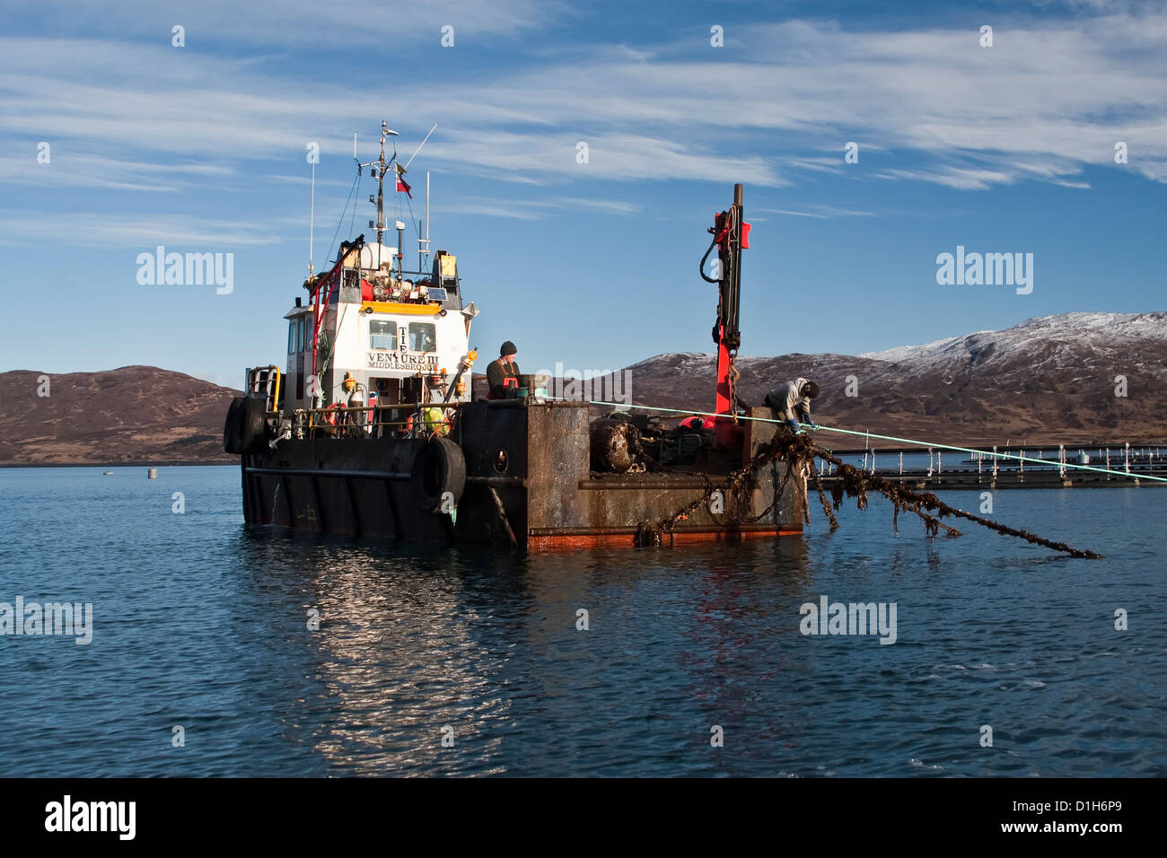 Fish farm boat fixing moorings at salmon farm, Loch Ainort, Isle of Skye, Scotland, UK Stock Photo