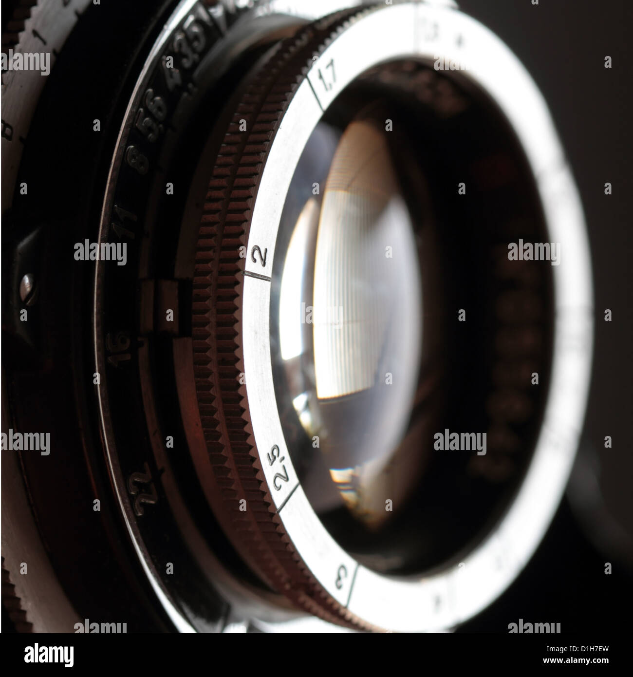 An old camera lens close-up on a dark background. Square format. Stock Photo