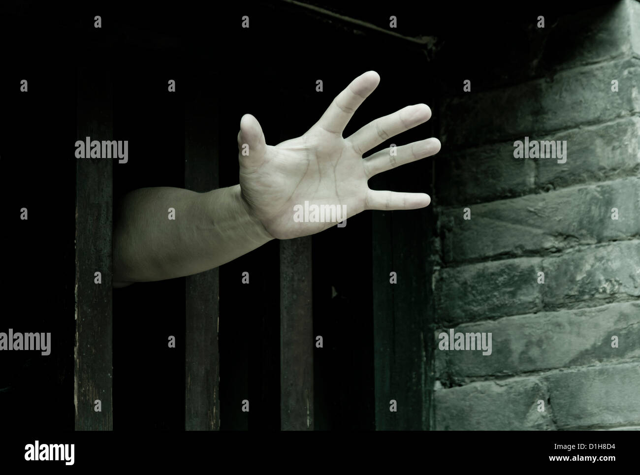 Prisoner hands stretch out from prison bars Stock Photo