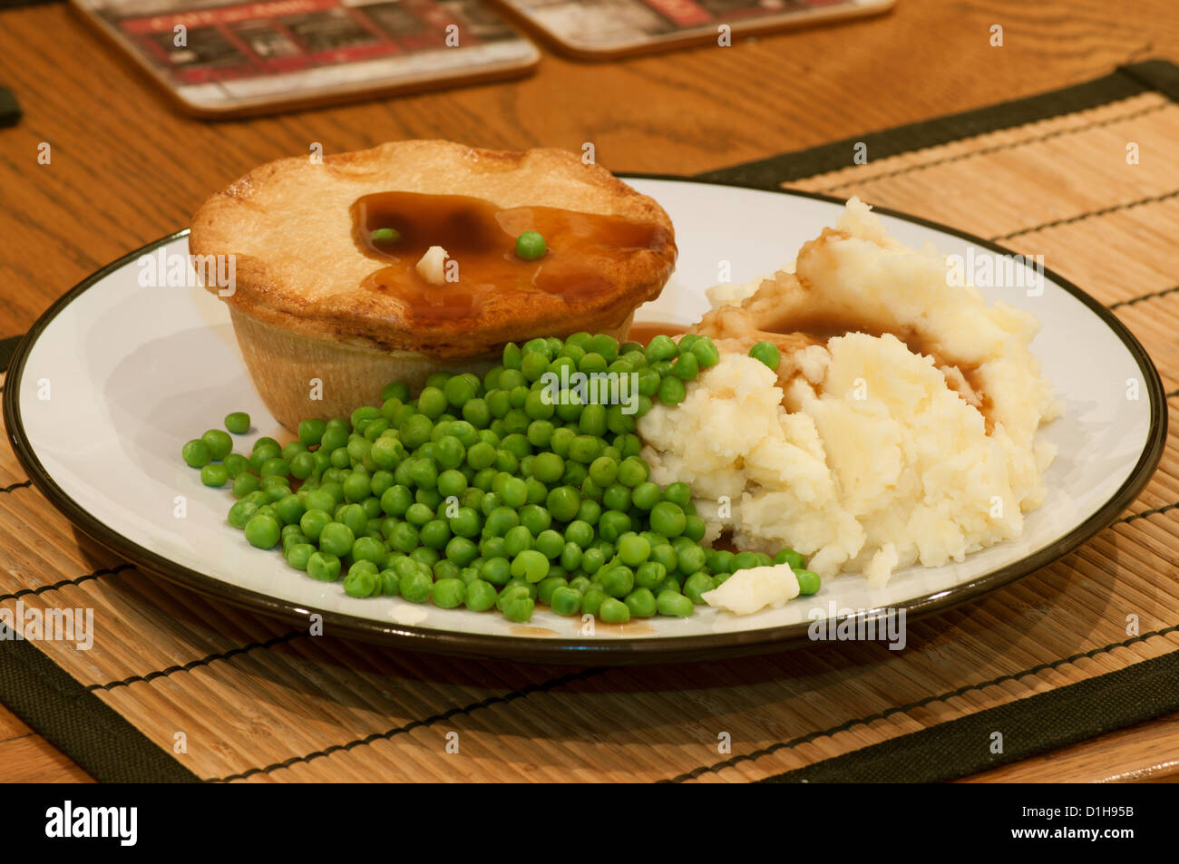 Hot Dinner Of meat Pie Mashed Potatoes and Peas on a Plate Stock Photo