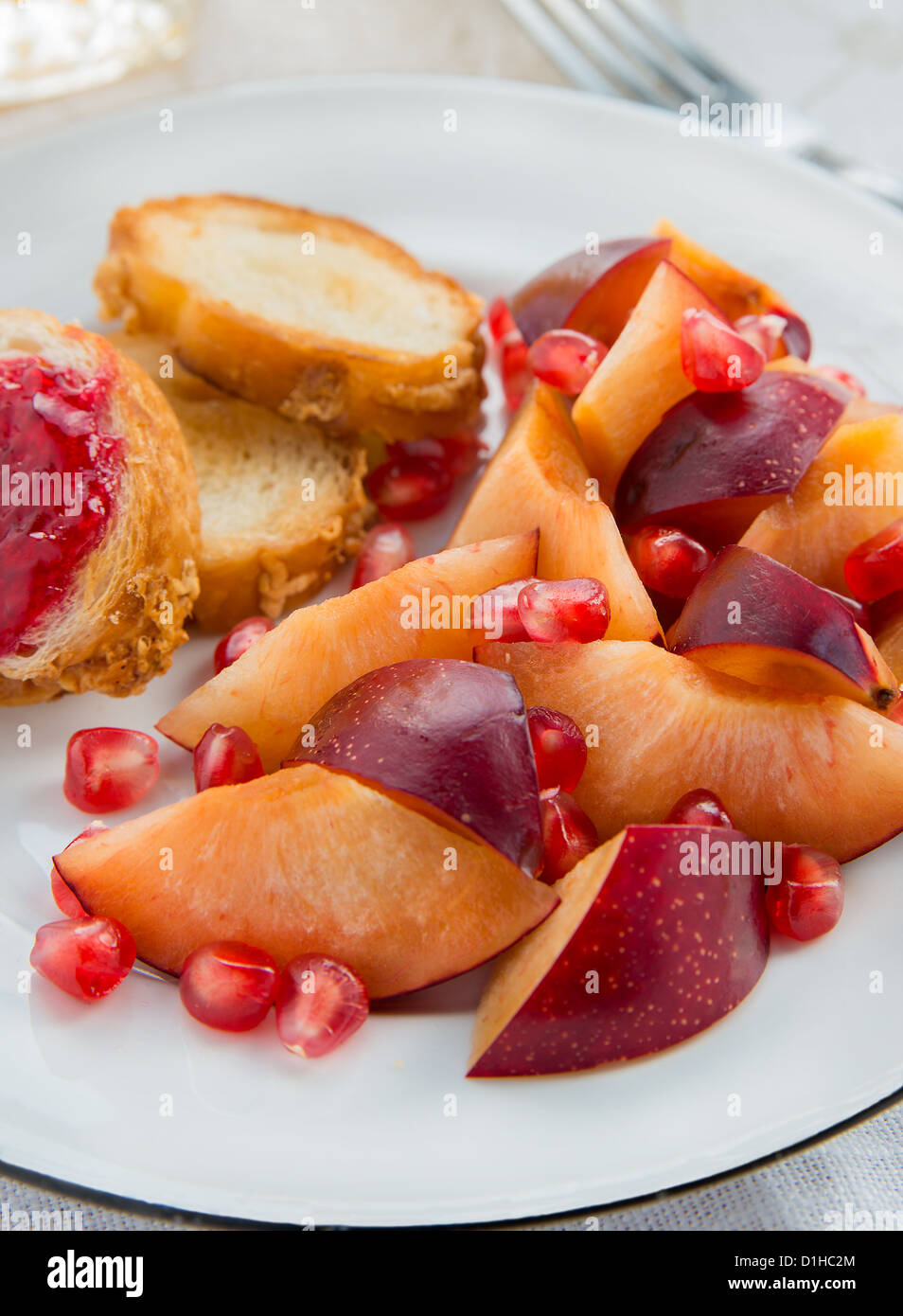 Sliced plum and pomegranate seeds on plate Stock Photo