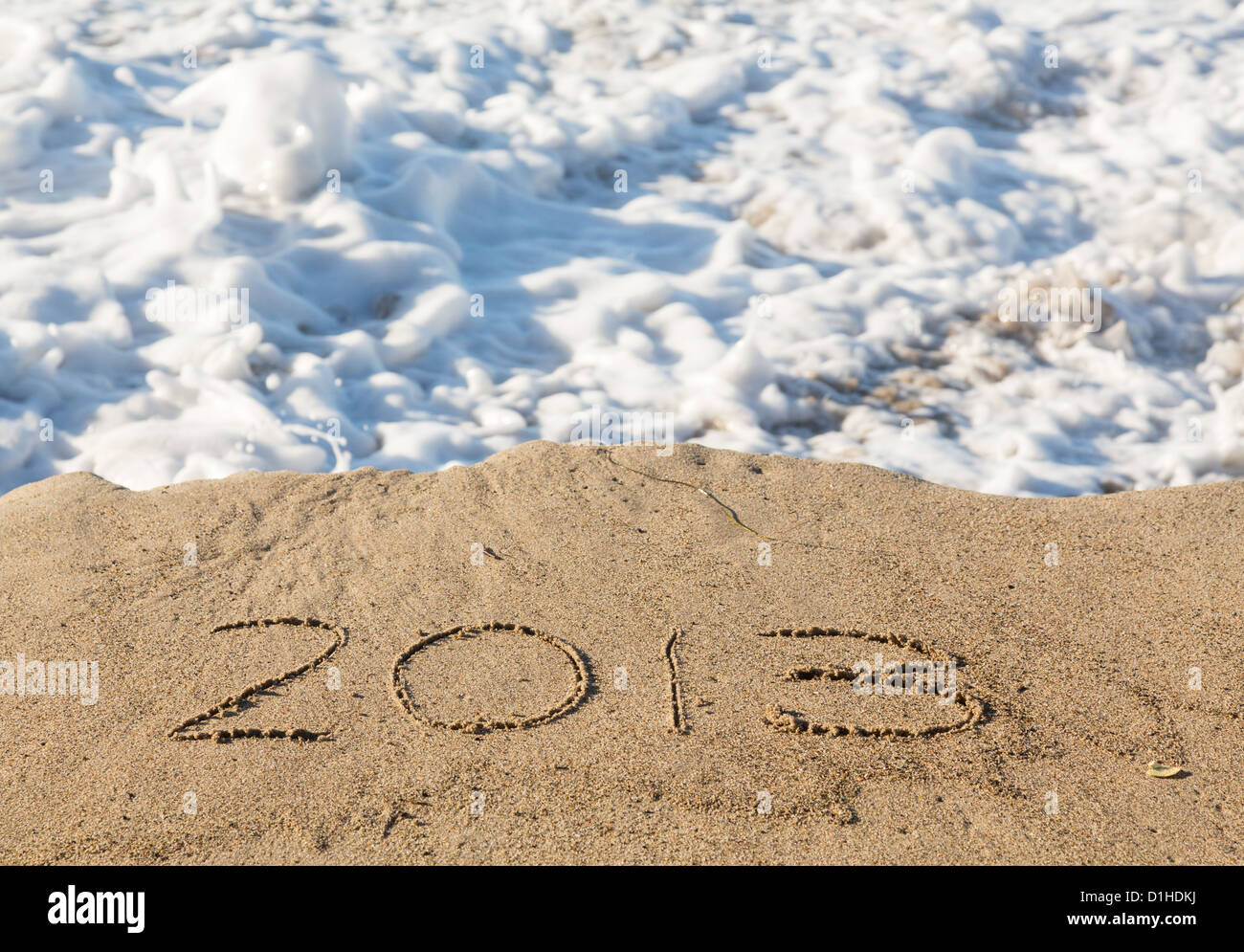 Calendar concept of 2013 written in sand on beach being covered by surf and waves Stock Photo