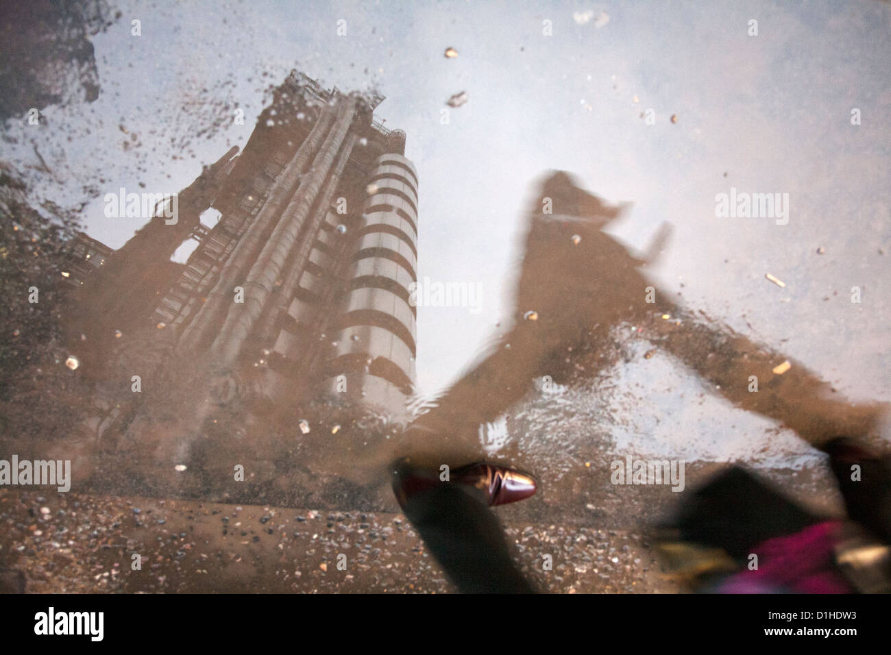 Reflection of Lloyd's Building and person walking across puddle on a
