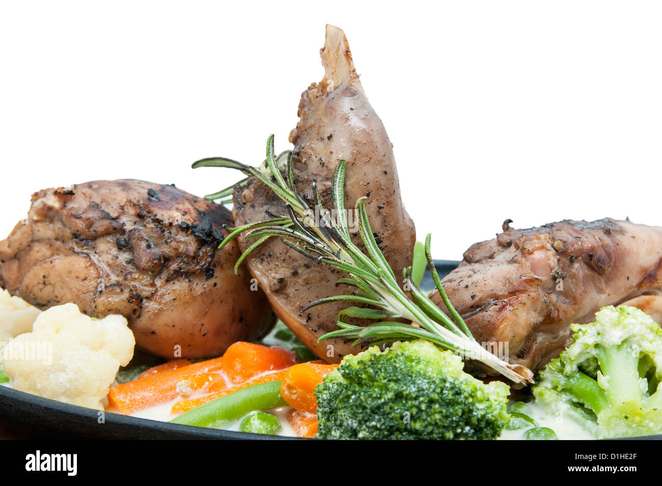Roasted rabbit meat and potatoes with vegetables in the plate on white background Stock Photo